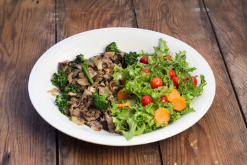 Warm mushroom salad on white plate and wooden background