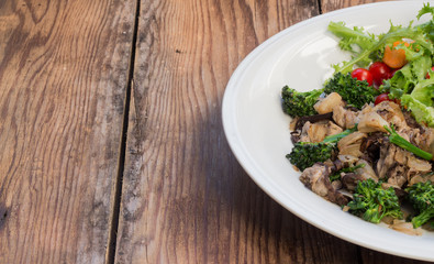 Warm mushroom salad on white plate and wooden background
