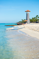 Fototapeta premium Beautiful day at sea. White sand, tropical palm trees and lighthouse on sandy shore