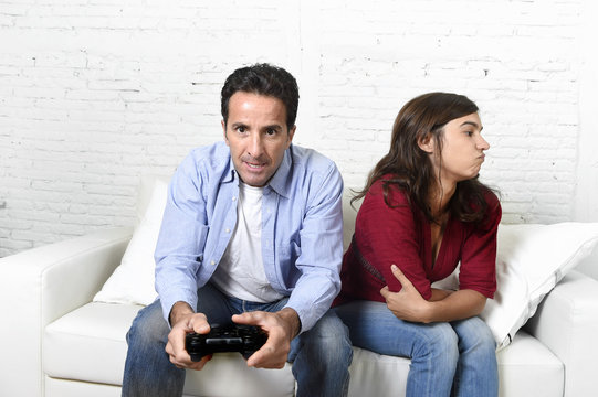 woman  angry and upset while husband or boyfriend plays videogames ignoring her