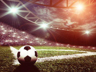 Soccer ball on green stadium, arena in night illuminated