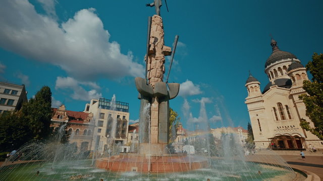 An ultra wide-angle shot featuring the Dormition of the Theotokos Cathedral and water fountain in Cluj Napoca, Romania
