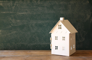 miniature toy house over chalkboard background. room for text