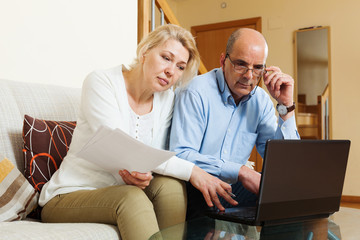  mature couple with financial documents and laptop
