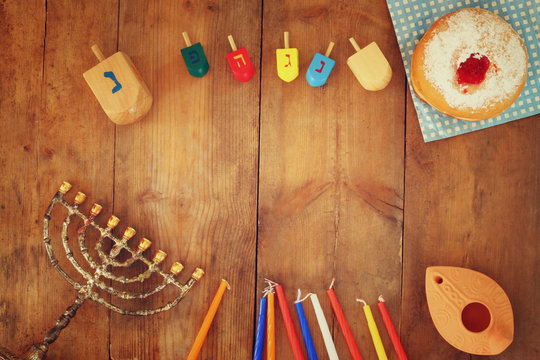top view image of jewish holiday Hanukkah with menorah (traditional Candelabra), donuts and wooden dreidels (spinning top). retro filtered image
