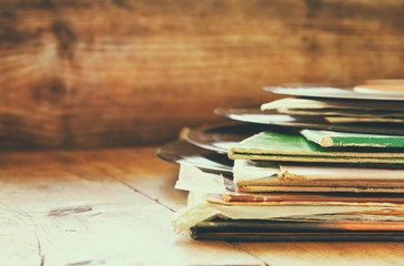 selective focus of records stack with record on top over wooden table. vintage filtered

