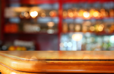 image of wooden table in front of abstract blurred background of restaurant lights
