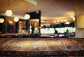 Poster image of wooden table in front of abstract blurred background of restaurant lights   © tomertu
