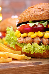 Grilled hamburger with fries, tomato, onion and corn on brick wa