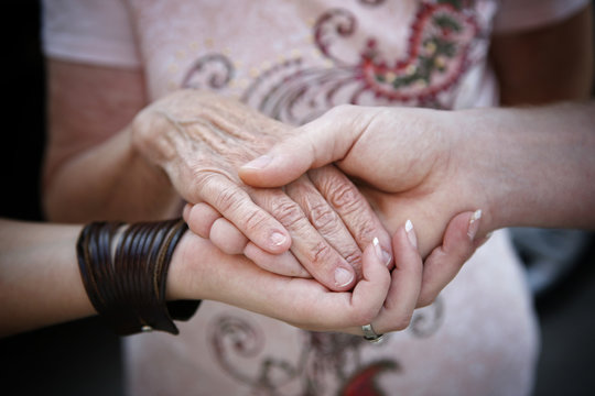 Helping elderly people concept - young hands supporting old hand