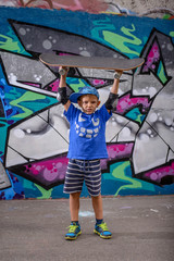 Obraz na płótnie Canvas Happy playful boy holding his skateboard