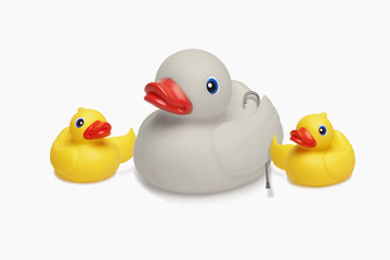 Two rubber ducklings support and assist an elderly rubber duck