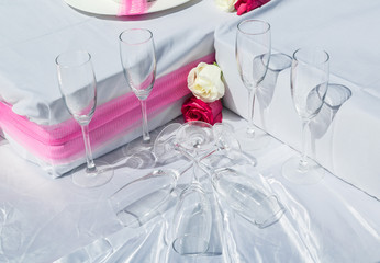 fragment of amazing gorgeous beautiful closeup view of wedding decorated part of table with glasses and roses on white grey sheet or cloth