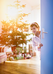 christmas morning, a girl opens a door.Christmas tree & gifts 