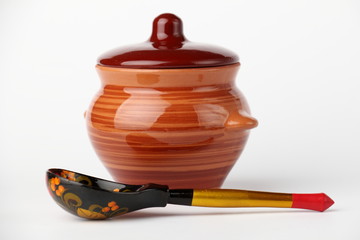 Ceramic pot and spoon./Spoon and ceramic pot with a lid on a white background.