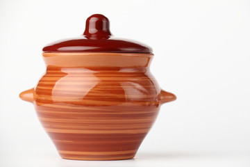Ceramic pot and spoon./Spoon and ceramic pot with a lid on a white background.