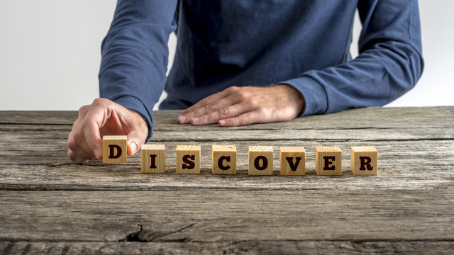 Front view of a man assembling word Discover with wooden cubes