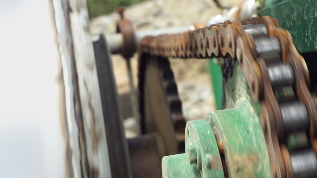 Close up shot of the chain and sprocket turning the drum of a magnetic separator used to separate iron out of other materials in the mining industry.