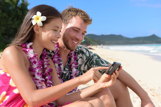 Couple on beach using smart phone on Hawaii
