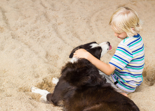 Young Boy With His Arm Around His Dog At The Beach With Copy-space