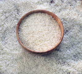 Rice in a wooden bowl on sackcloth background