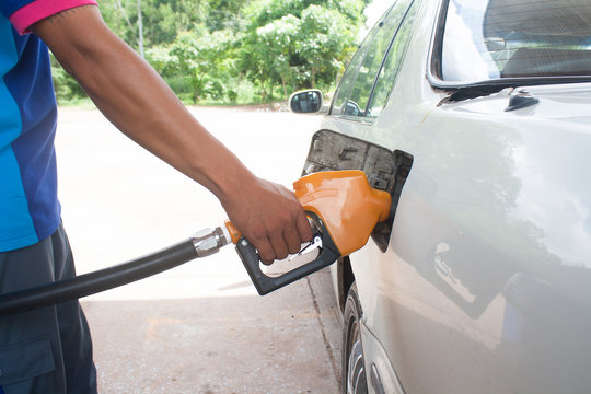 Hand hold Fuel nozzle to add fuel in car at filling station. Focus on the handle arm.