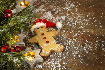 Christmas gingerbread in red hat and snow on a wooden background