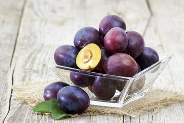 fresh plums in a bowl on old wooden background