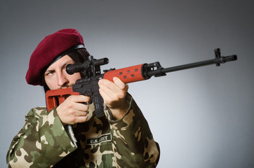 Fototapeta premium Soldier with handgun against gray