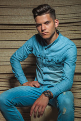  man in wooden studio sitting on a chair and posing