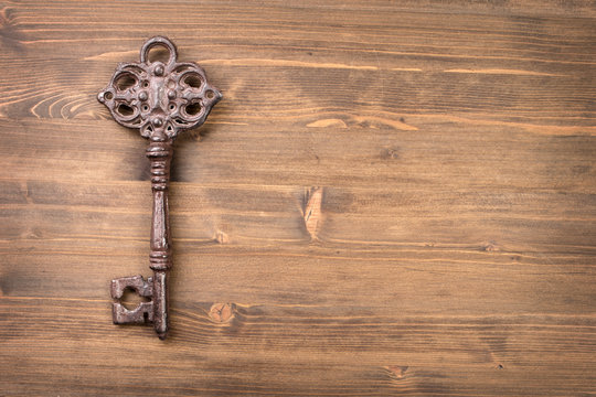 Old vintage key from left side of wooden background