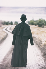 Stylized portrait of a man in garrick coat walking on the rural path