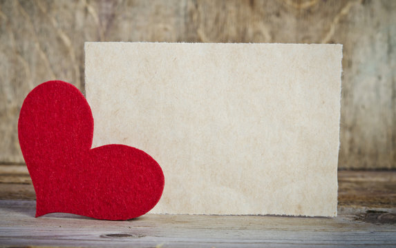 the form for a card on wooden background .   handmade heart from