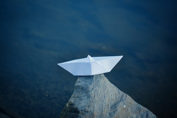 White paper ship sailing on blue water surface.