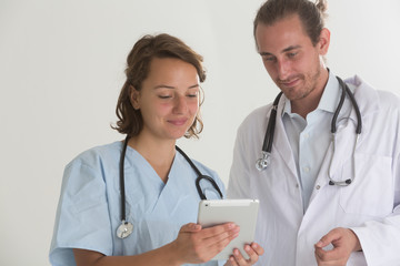 Two doctors consulting and filling out medical documents on a tablet computer