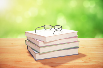 Stack of books and glasses on a wooden table in the summer park