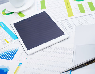Tablet on desk and financial papers