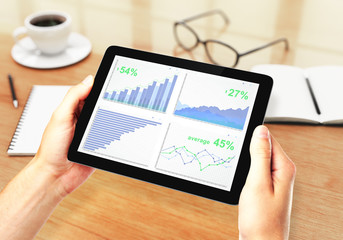 Men's hands holding a digital tablet with financial charts