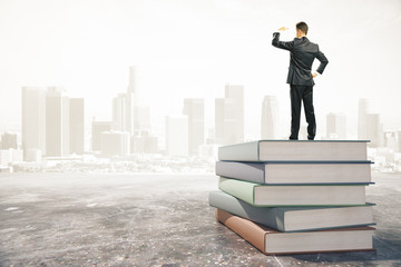 Businessman standing on a stack of books and looks away