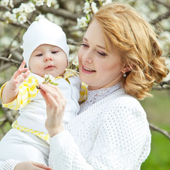 Happy mother are walking with newborn in a spring park 