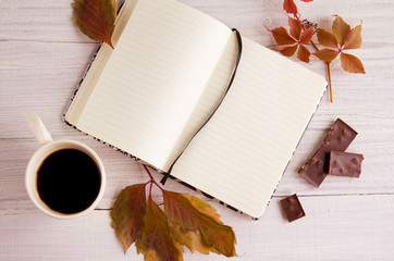 Autumn still life with  cup of coffee, notebook, leaves and chocolate