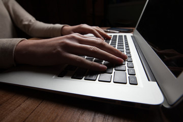 woman hands using laptop at office desk, with copyspace in dark