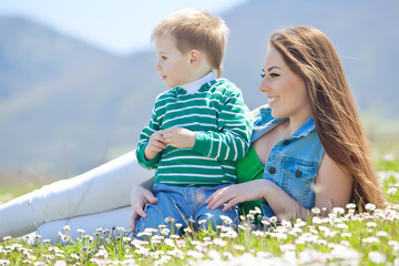 Happy mother with son in a flowers field 