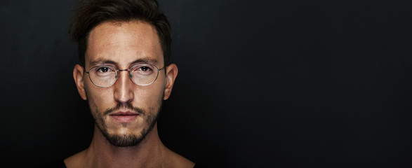 Portrait of cute young man wearing glasses and looking at the camera. Wide