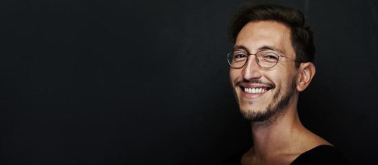 Portrait of smiling handsome man wearing glasses and looking at the camera. Wide