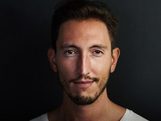 Portrait of cute young man wearing white tshirt and smiling at the camera. Horizontal