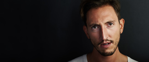 Obraz premium Portrait of young man wearing white tshirt and looks angry. Wide