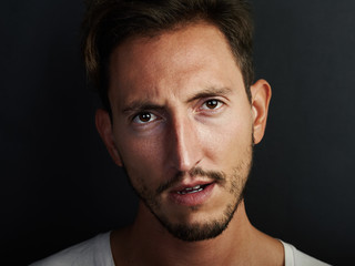 Obraz premium Portrait of young man wearing white tshirt and looks angry. Horizontal