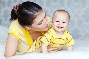 Happy mother with her baby in the morning bed