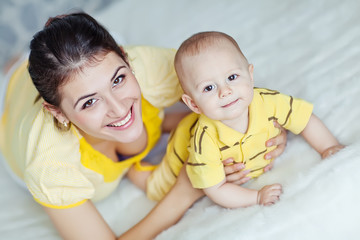 Happy mother with her baby in the morning bed